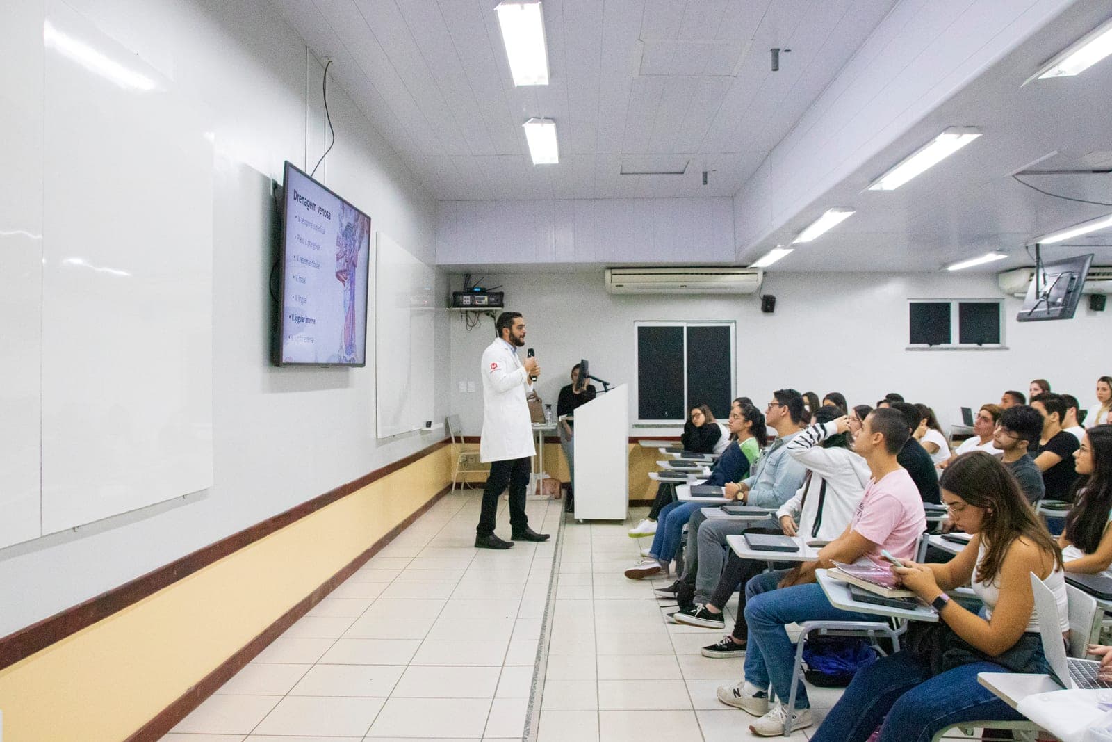 Dr. Jônatas dando aula teórica de anatomia em auditório cheio de estudantes